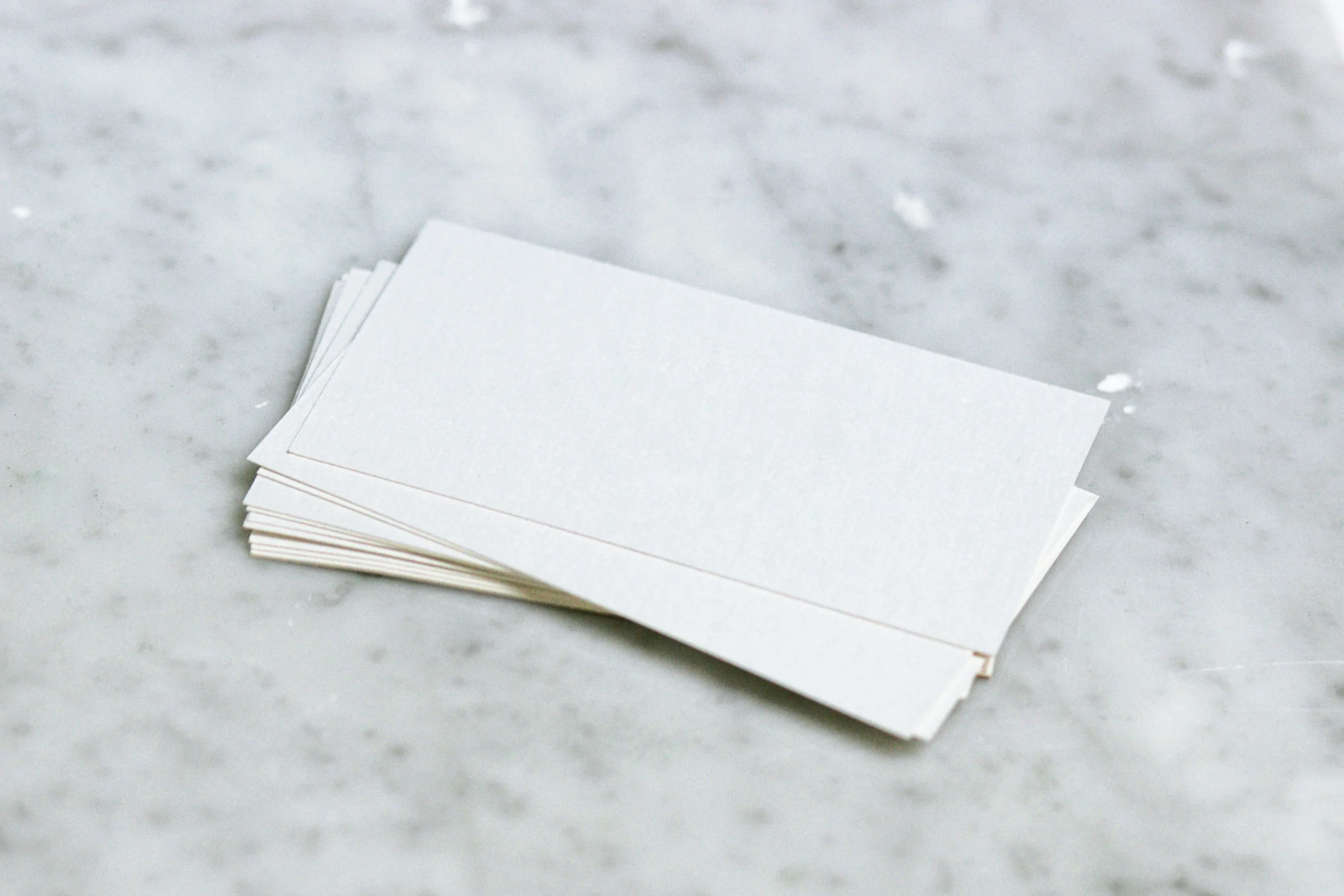 Stack of blank business cards on a marble surface.